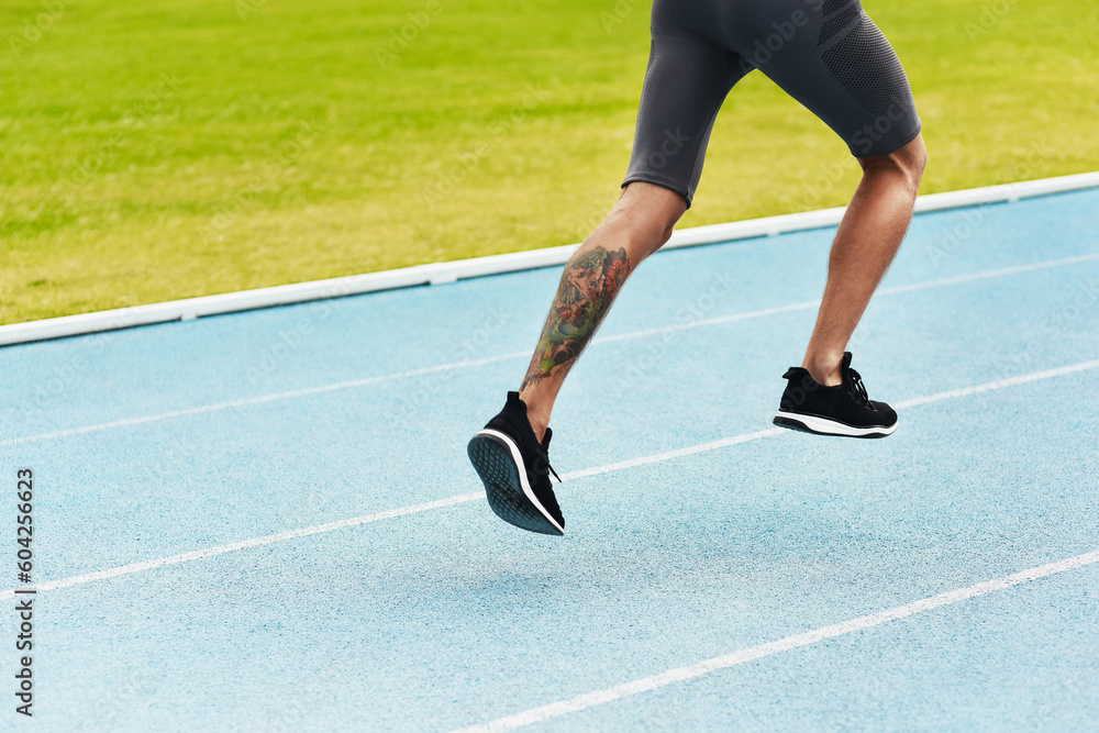 Man, legs and running on track for athletics, fitness or exercise of athlete training at the stadium. Leg of male person or runner exercising in run, workout or sports competition for healthy cardio