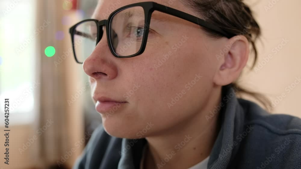 Close-up of face of pensive brunette girl with glasses with blue eyes in slow motion. Serious focused face young woman. Woman with relaxed facial expression. Close-up of face of pensive brunette girl with glasses with blue eyes in slow motion. Serious focused face young woman. Woman with relaxed facial expression.