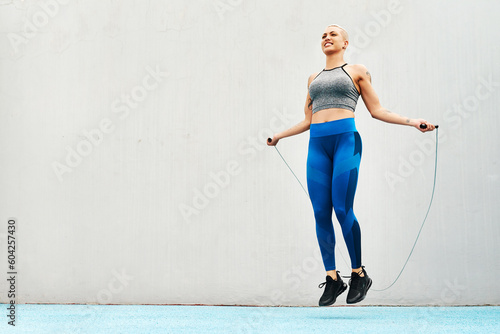 Jump, rope and woman skipping against space in stadium for sports, workout practice and cardio. Performance, health and body with female athlete training on track for strong, mockup and exercise