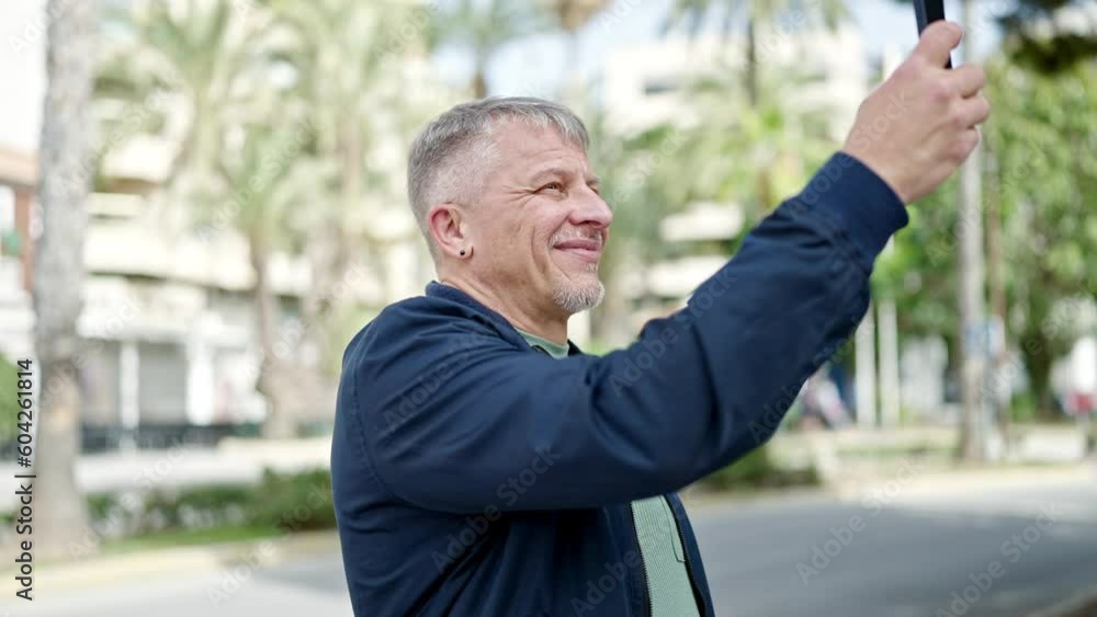 Middle age grey-haired man smiling confident reacording video by smartphone at park Middle age grey-haired man smiling confident reacording video by smartphone at park