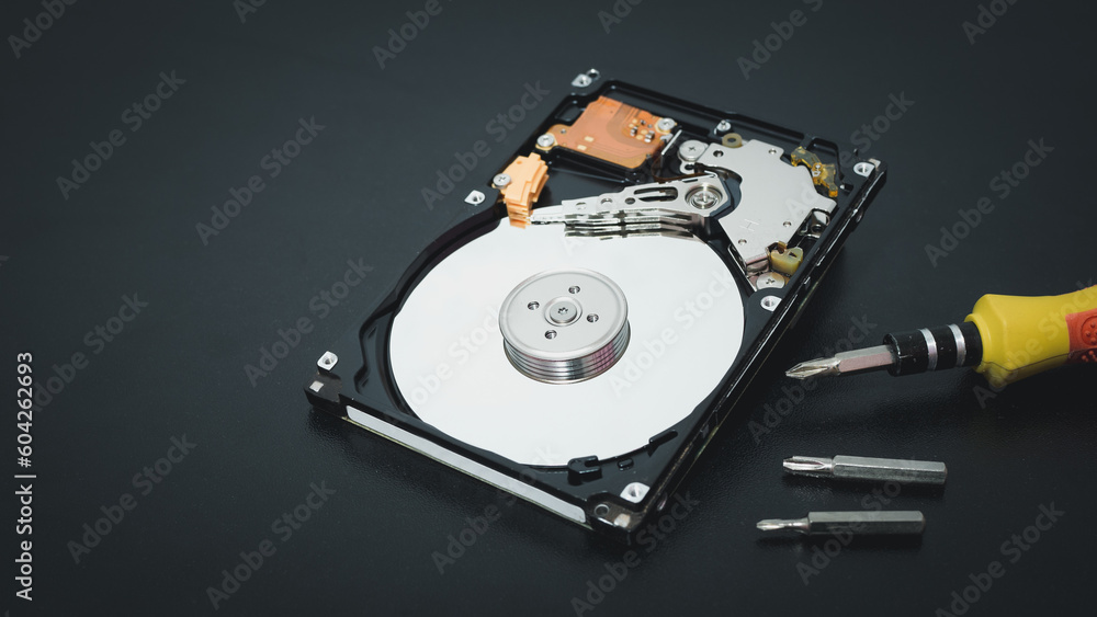 Memory repair concept. Repair of storage systems. Hard disk repair. Hard disk with screwdriver on dark background Memory repair concept. Repair of storage systems. Hard disk repair. Hard disk with screwdriver on dark background