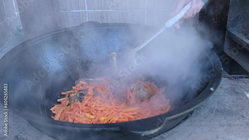 Wallpaper Mural Female hand stirs pilaf which steam rises, lamb meat with tail fat. Cooking in cauldron on the street kitchen.  Torontodigital.ca