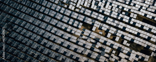 Stunning aerial view of a solar farm, casting geometric shadows on sleek panels amidst contrasting landscape, evoking emotions in eco-friendly innovation. Generative AI