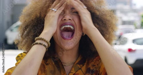 Face, stress and shout with an african woman on a camcorder outdoor in the city for crazy expression. Portrait, mental health and scream with a young female person on an urban street to show emotions photo