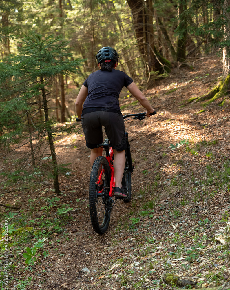 Female cyclist on her mountain bike riding through the hills on a sunny day.