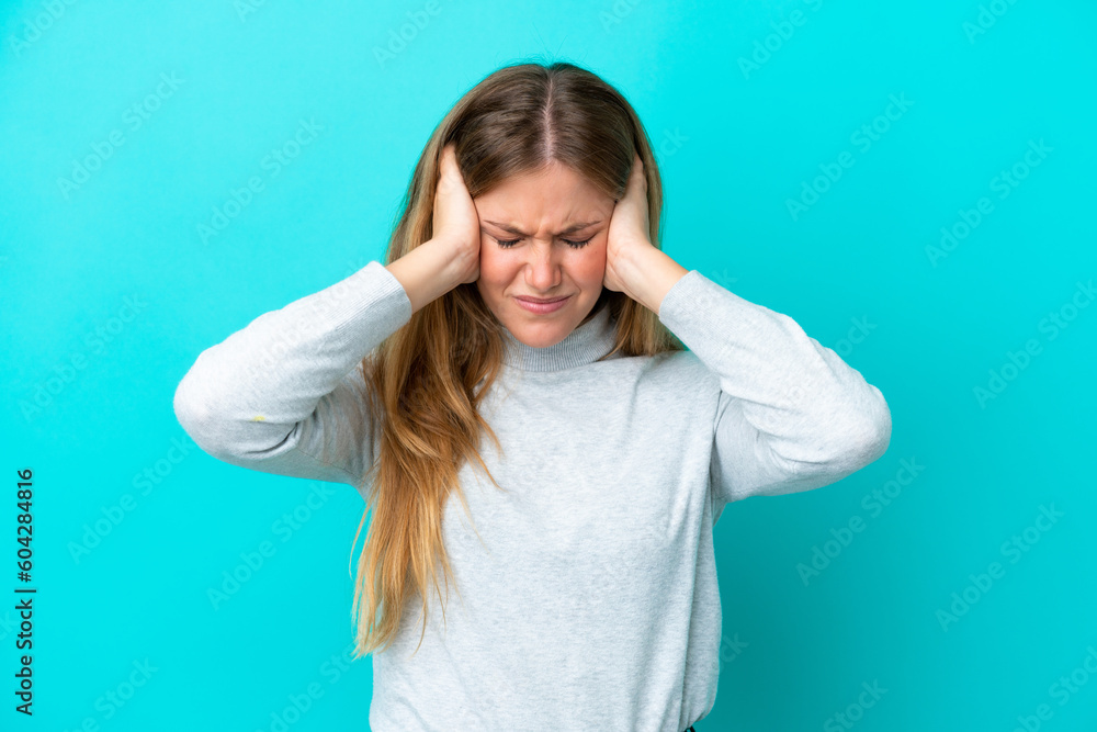 Young blonde woman isolated on blue background frustrated and covering ears Young blonde woman isolated on blue background frustrated and covering ears