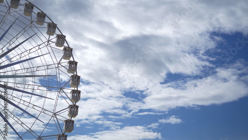 Half Ferris wheel, in front of a blue sky with white clouds, stock photo