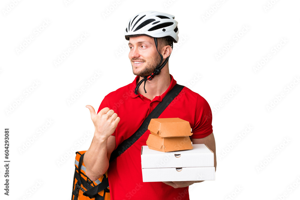 Young delivery man taking a takeaway food over isolated chroma key background pointing to the side to present a product Young delivery man taking a takeaway food over isolated chroma key background pointing to the side to present a product