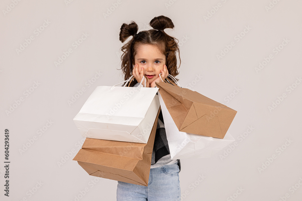 Black Friday. Attention sale. Surprised happy little girl with shopping bags on a white background. Seasonal discounts. Seasonal sales. Auction goods. Black Friday. Attention sale. Surprised happy little girl with shopping bags on a white background. Seasonal discounts. Seasonal sales. Auction goods.