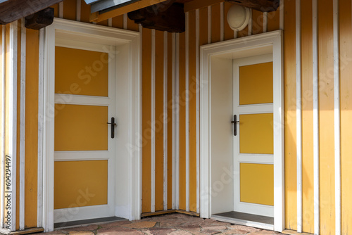 Two opposite yellow entrance doors at the front of the wooden house
