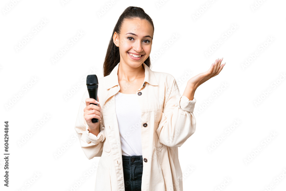 Young singer woman picking up a microphone over isolated chroma key background extending hands to the side for inviting to come Young singer woman picking up a microphone over isolated chroma key background extending hands to the side for inviting to come