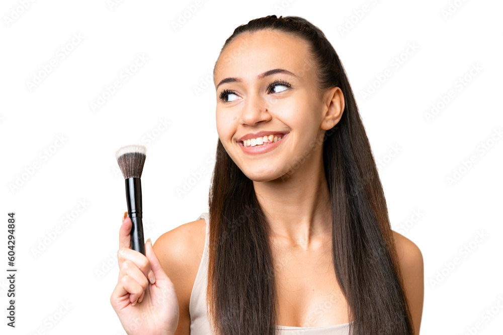 Young Arabian woman over isolated chroma key background holding makeup brush and looking up Young Arabian woman over isolated chroma key background holding makeup brush and looking up