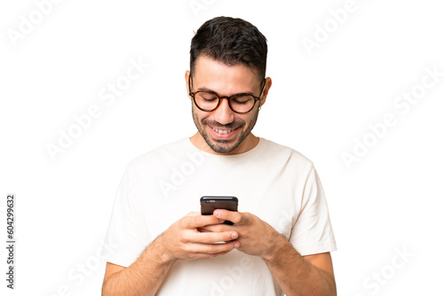 Young handsome caucasian man over isolated chroma key background sending a message with the mobile © luismolinero