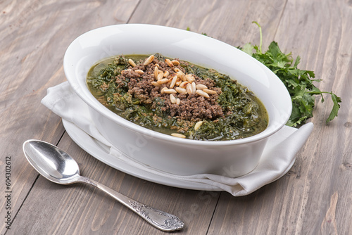 Oriental food of mulukhiyah topped with minced meat and pine seeds, Molokhia Arabian food , spinach with minced meat