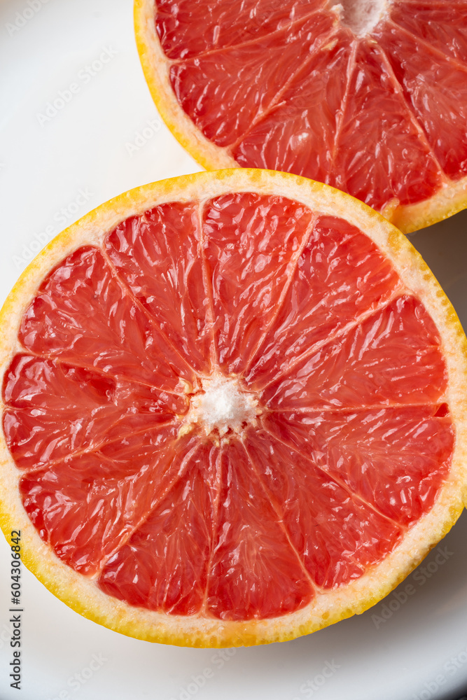 Macro overhead view of cut red grapefruit on white plate, selective focus, vertical, with copy space Macro overhead view of cut red grapefruit on white plate, selective focus, vertical, with copy space