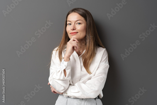 Happy young businesswoman posing isolated over grey wall background. A studio shot of an adult woman standing with a smiling expression