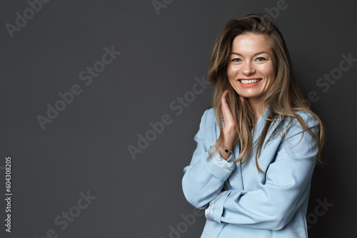Happy young businesswoman posing isolated over black wall background. A studio shot of an adult woman standing with a smiling expression