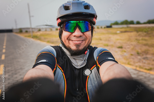 Self portrait of happy male cyclist outdoors. Happy Cyclist with glasses and helmet taking a selfie