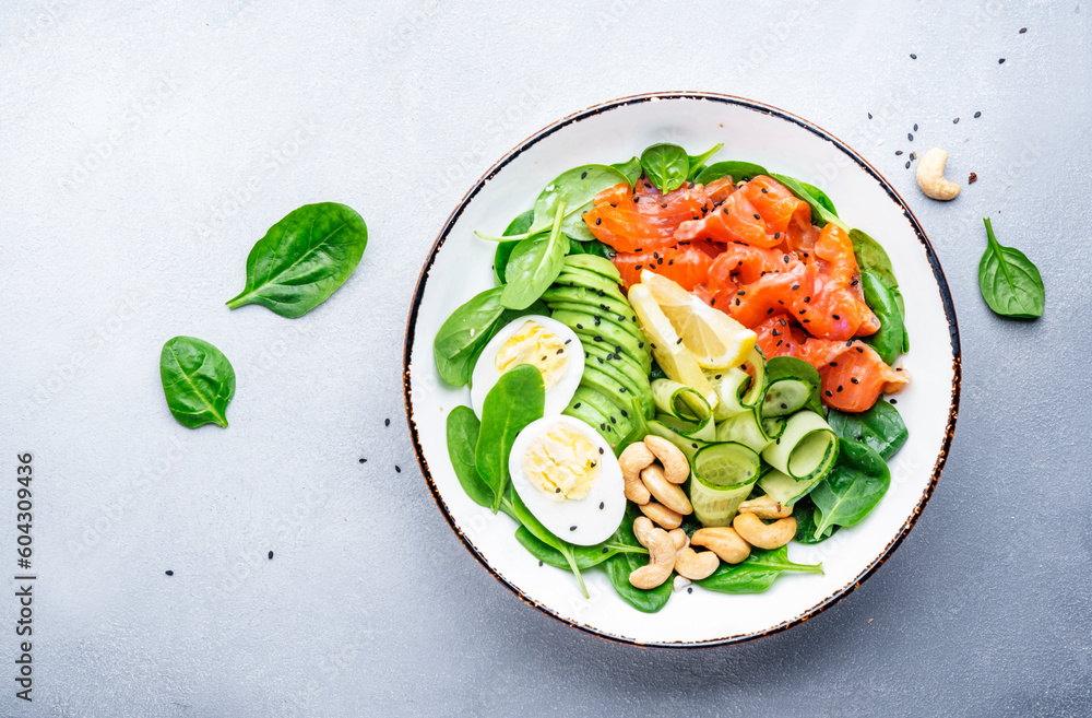 Ketogenic salad with salted salmon, avocado, spinach, cucumber, eggs and cashew nuts. Low-carbohydrate breakfast rich in healthy fats. Gray table background, top view Ketogenic salad with salted salmon, avocado, spinach, cucumber, eggs and cashew nuts. Low-carbohydrate breakfast rich in healthy fats. Gray table background, top view