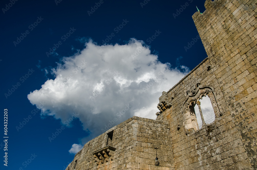 The photo captures the majestic, intact walls of an ancient Portuguese castle, against the backdrop of a clear, sunny sky with a solitary cloud, evoking a sense of timeless beauty and history.