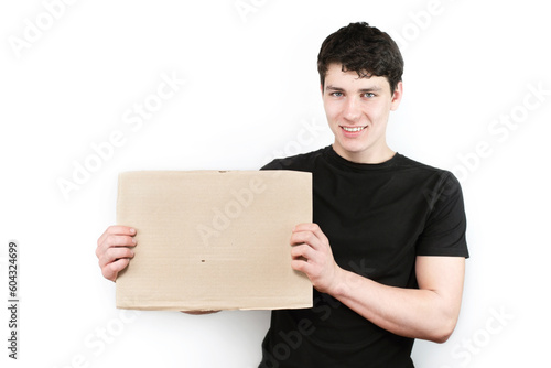 Cute young man on a white background with a sign in his hands, place for text, advertising. The guy is smiling and has a sign in his hands for inscriptions, a logo