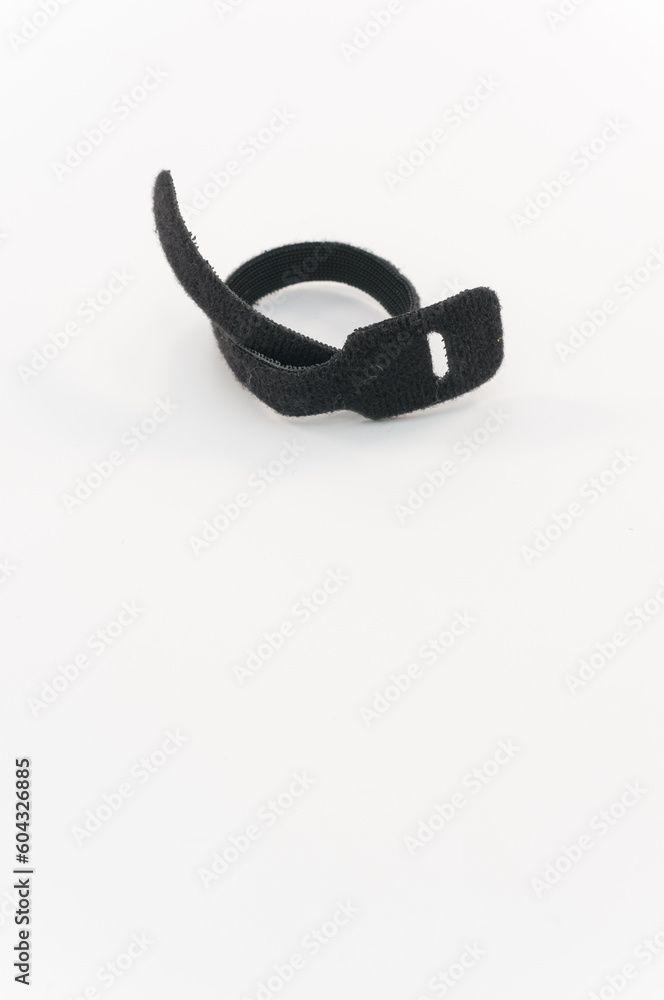 immagine primo piano con fascetta in materiale velcro per serrare, ordinare cavi su superficie di lavoro bianca immagine primo piano con fascetta in materiale velcro per serrare, ordinare cavi su superficie di lavoro bianca