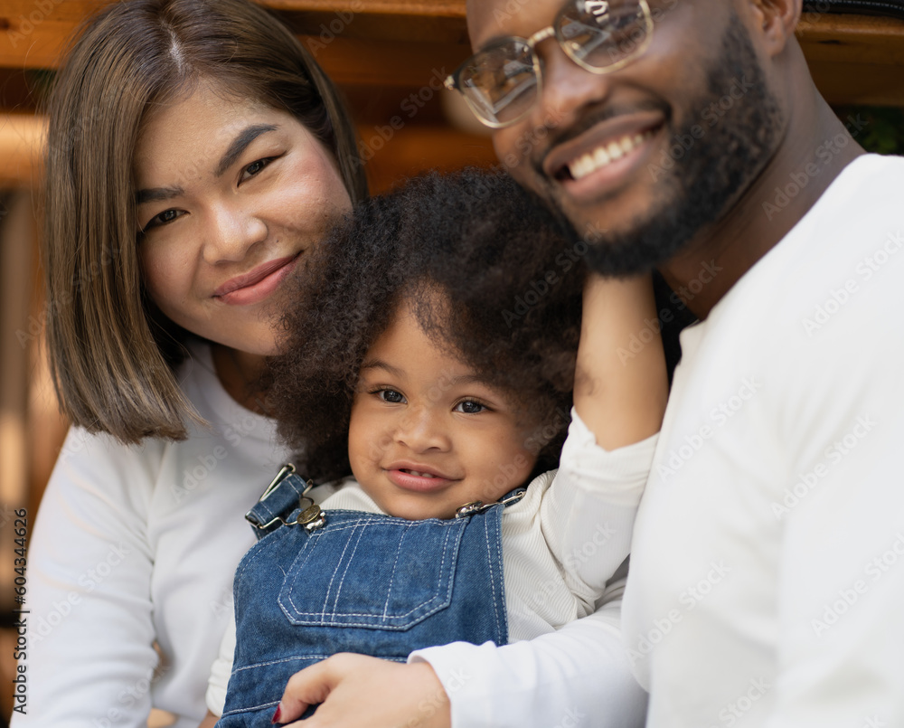 Smiling biracial child and family have fun together outdoors. Portrait of father and Asian mother happy leisure playing with cheerful multiracial daughter in backyard. Kid enjoying childhood laughing. Smiling biracial child and family have fun together outdoors. Portrait of father and Asian mother happy leisure playing with cheerful multiracial daughter in backyard. Kid enjoying childhood laughing.