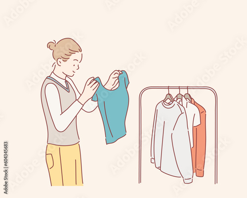 Beautiful young woman near rack with clothes making chioce. Hand drawn style vector design illustrations.