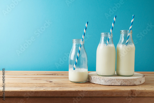 Milk bottles on wooden table over blue background