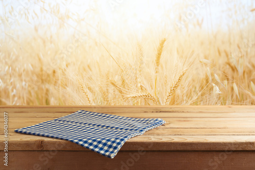 Empty wooden table with tablecloth over wheat field blurred background