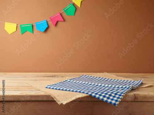 Brazilian Festa Junina summer harvest festival concept. Empty wooden table with tablecloth over wall  background. Mock up for design and product display photo