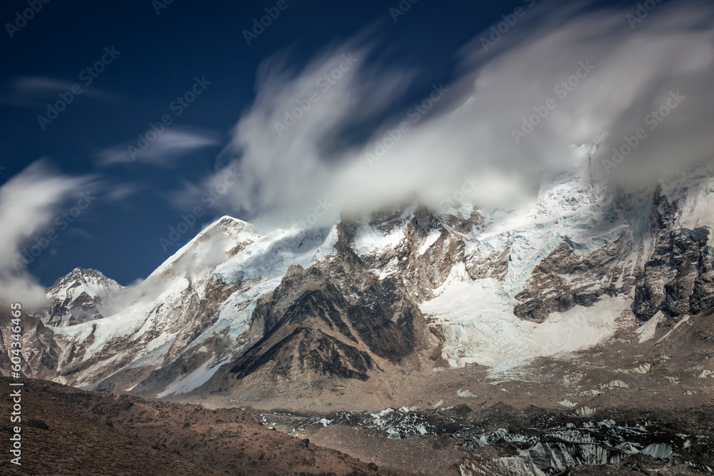 Snow capped mountains hidden behind blurred fast moving clouds in daylight, Nepal, Himalayas