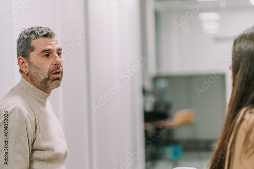 A close up photo of good looking middle-aged male business person talking to his female colleague at the office. Discussing marketing