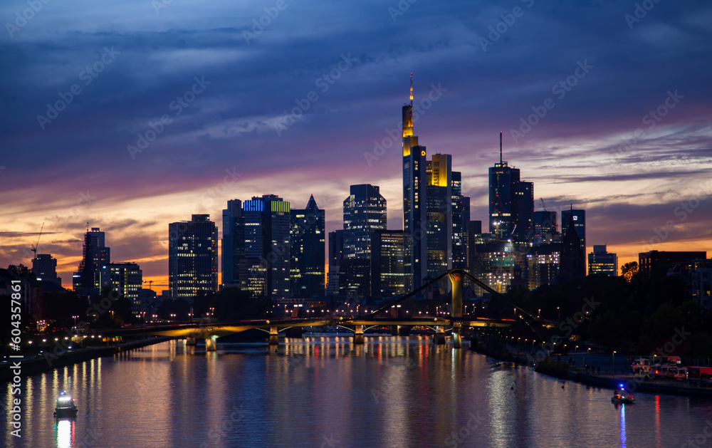 Captivating  of a Frankfurt's skyline at sunset, featuring a bridge, traffic, skyscrapers, and colorful reflections in the river.