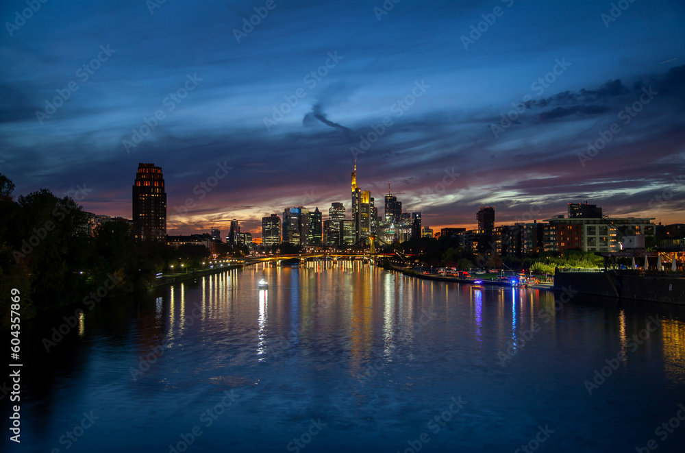 Stunning  of Frankfurt cityscape at sunset featuring skyscrapers, bridge traffic, and colorful river reflections in the background – perfect for urban backgrounds and commercials.