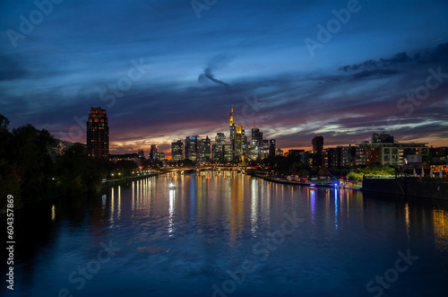 Stunning of Frankfurt cityscape at sunset featuring skyscrapers, bridge traffic, and colorful river reflections in the background – perfect for urban backgrounds and commercials.
