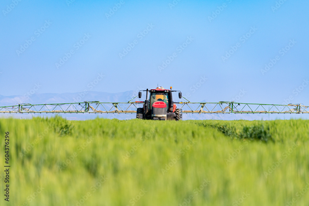 Tractor spray fertilizer on green field. Farming tractor plowing and spraying on field. Tractor spray fertilizer on green field. Farming tractor plowing and spraying on field.