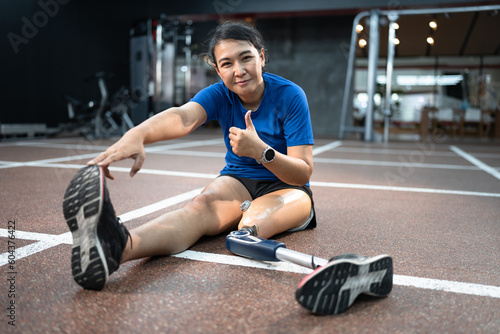 Happy Asia woman with prosthetic leg exercise at gym or fitness 