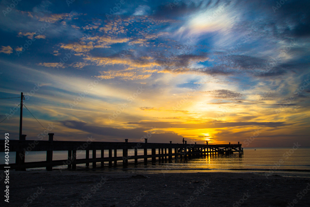 The sun is rising over the sea in the morning, with a concrete bridge in the foreground. The sun is rising over the sea in the morning, with a concrete bridge in the foreground.