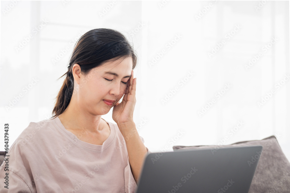 Office syndrome concept. mature middle age asian woman feeling pain in neck and shoulder after working on computer laptop for a long time. She stretches to relax her muscles Office syndrome concept. mature middle age asian woman feeling pain in neck and shoulder after working on computer laptop for a long time. She stretches to relax her muscles