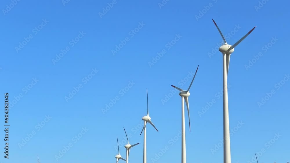 Wind turbines provide clean energy and are a sustainable solution to global warming. Panoramic view on a blue sky background is a symbol of renewable green power. Wind turbines provide clean energy and are a sustainable solution to global warming. Panoramic view on a blue sky background is a symbol of renewable green power.