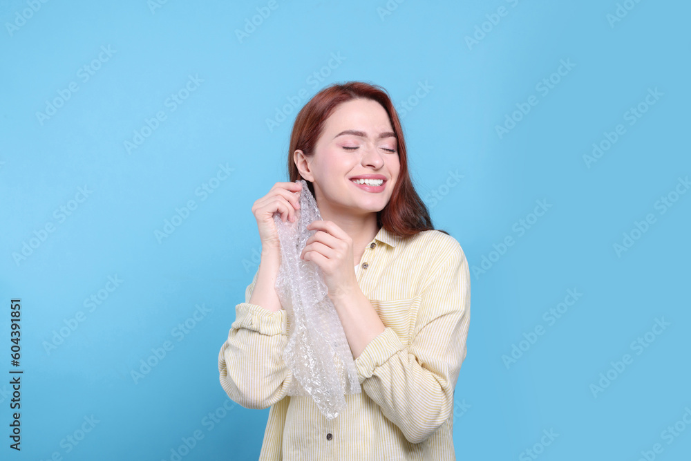Woman popping bubble wrap on turquoise background. Stress relief Woman popping bubble wrap on turquoise background. Stress relief