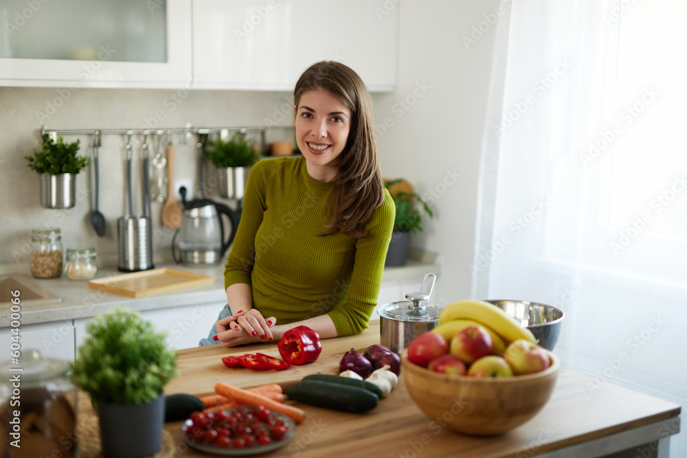 Woman chopping red bell pepper on the wooden board in the kitchen Woman chopping red bell pepper on the wooden board in the kitchen