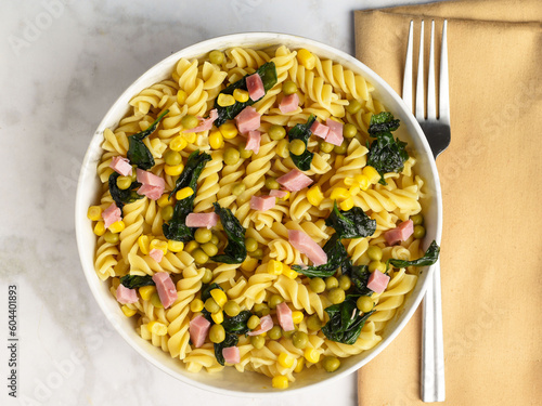 rotini pasta  with corn peas and dhan with sauteed spinach, photo