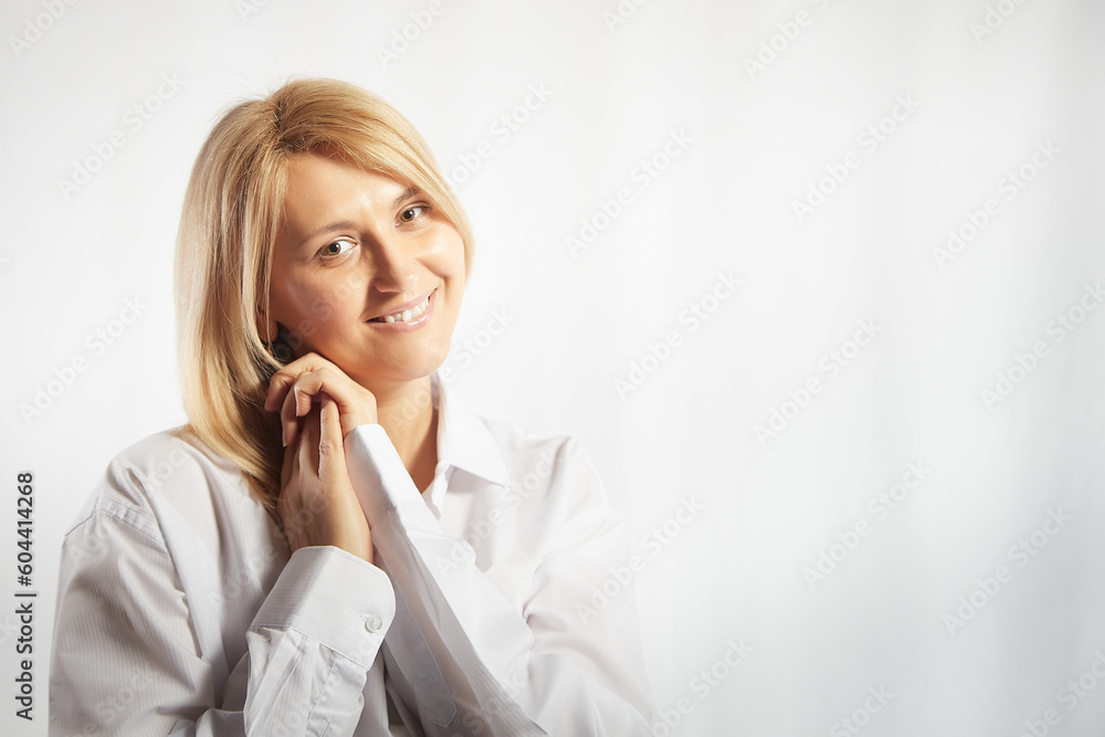 Portrait of a pretty calm sweet blonde smiling woman posing on a white background. Happy girl model in white shirt in studio. Copy space Portrait of a pretty calm sweet blonde smiling woman posing on a white background. Happy girl model in white shirt in studio. Copy space