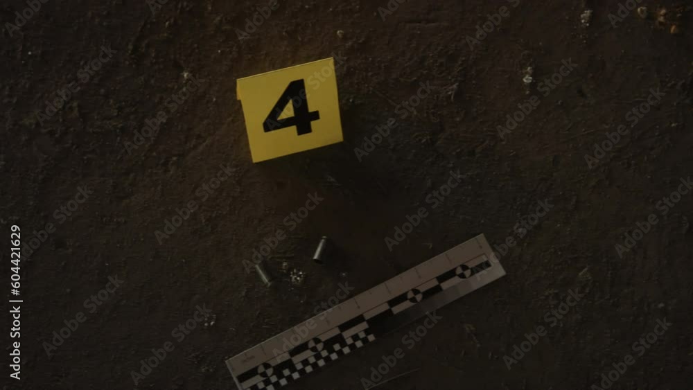 Close-up handheld top shot of yellow forensic marker with number 4 ...