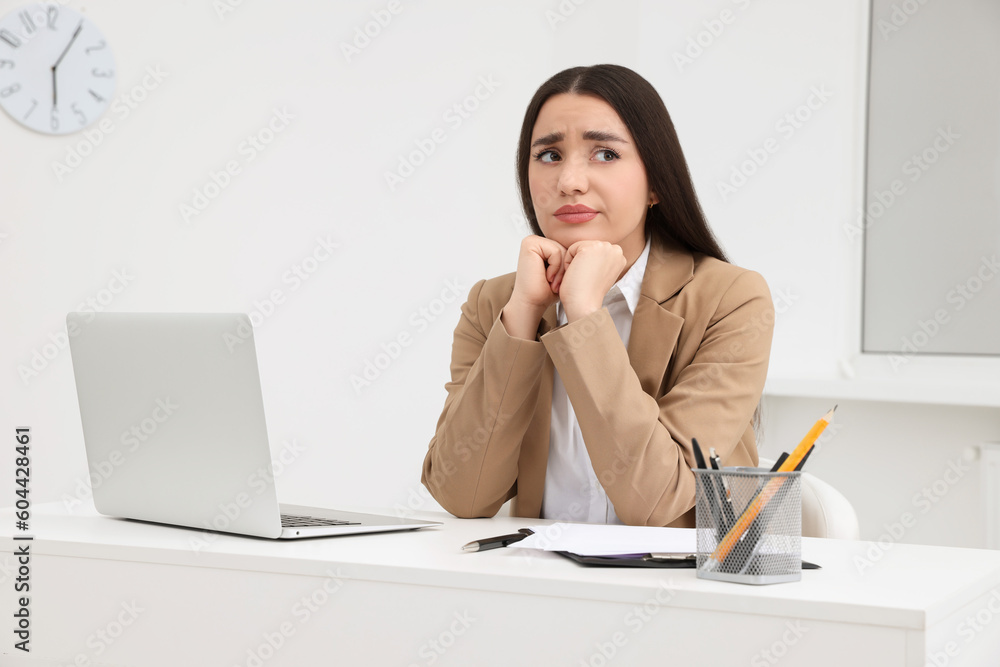 Unhappy young female intern at table in office Unhappy young female intern at table in office