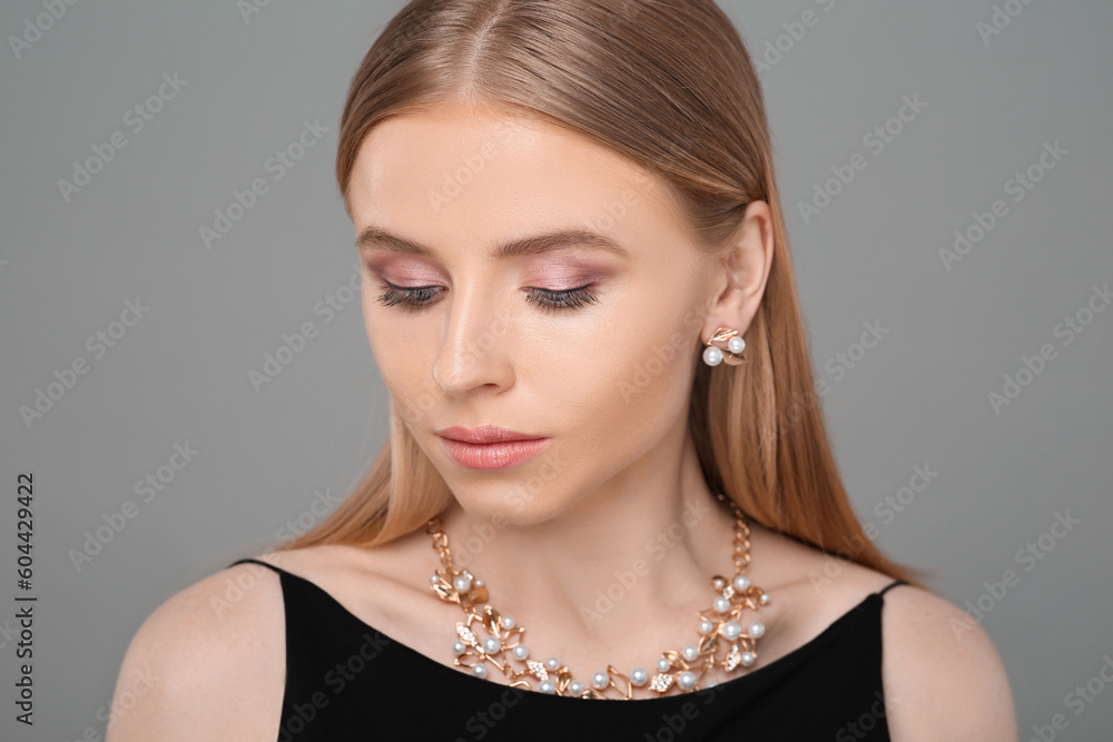 Beautiful young woman with elegant jewelry on gray background Beautiful young woman with elegant jewelry on gray background