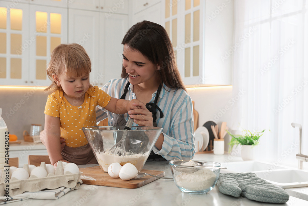 Mother and her little daughter cooking dough together in kitchen Mother and her little daughter cooking dough together in kitchen