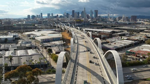 2023 - Excellent aerial footage of cars driving across the 6th Street Viaduct into Los Angeles, California on an overcast day.